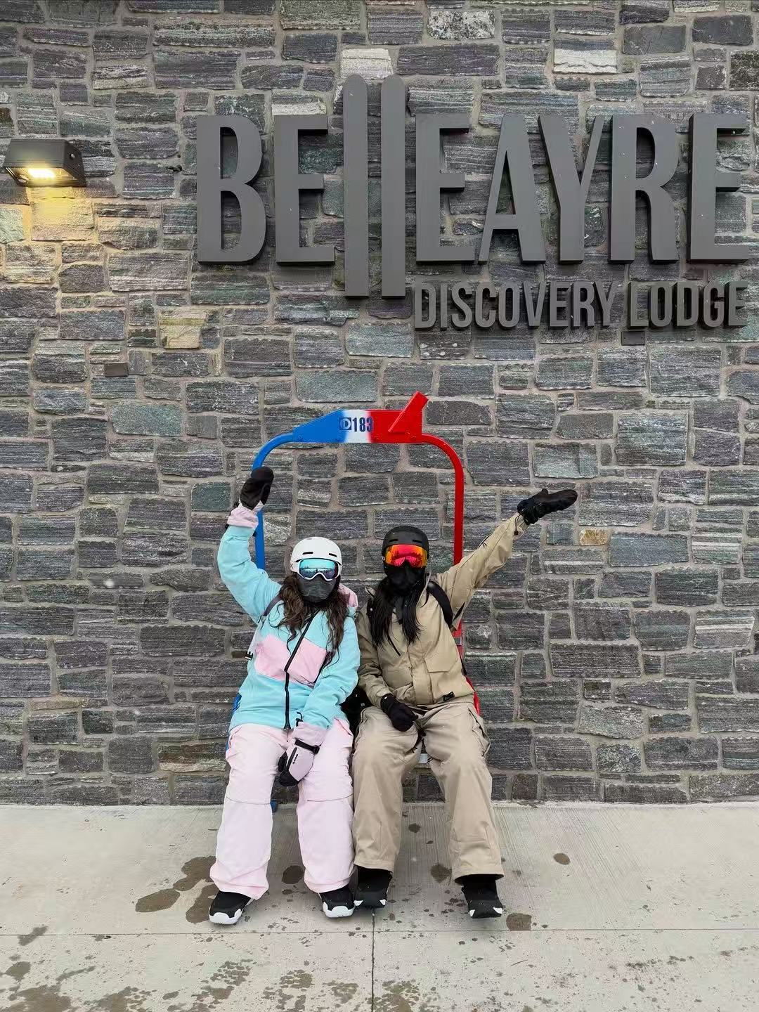 Two skiers wearing HIGH EXPERIENCE outfits at a ski resort