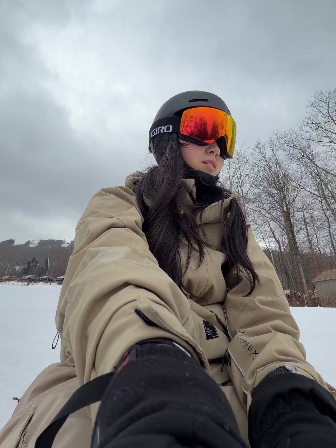 Skier wearing a beige HIGH EXPERIENCE ski outfit at a snowy resort