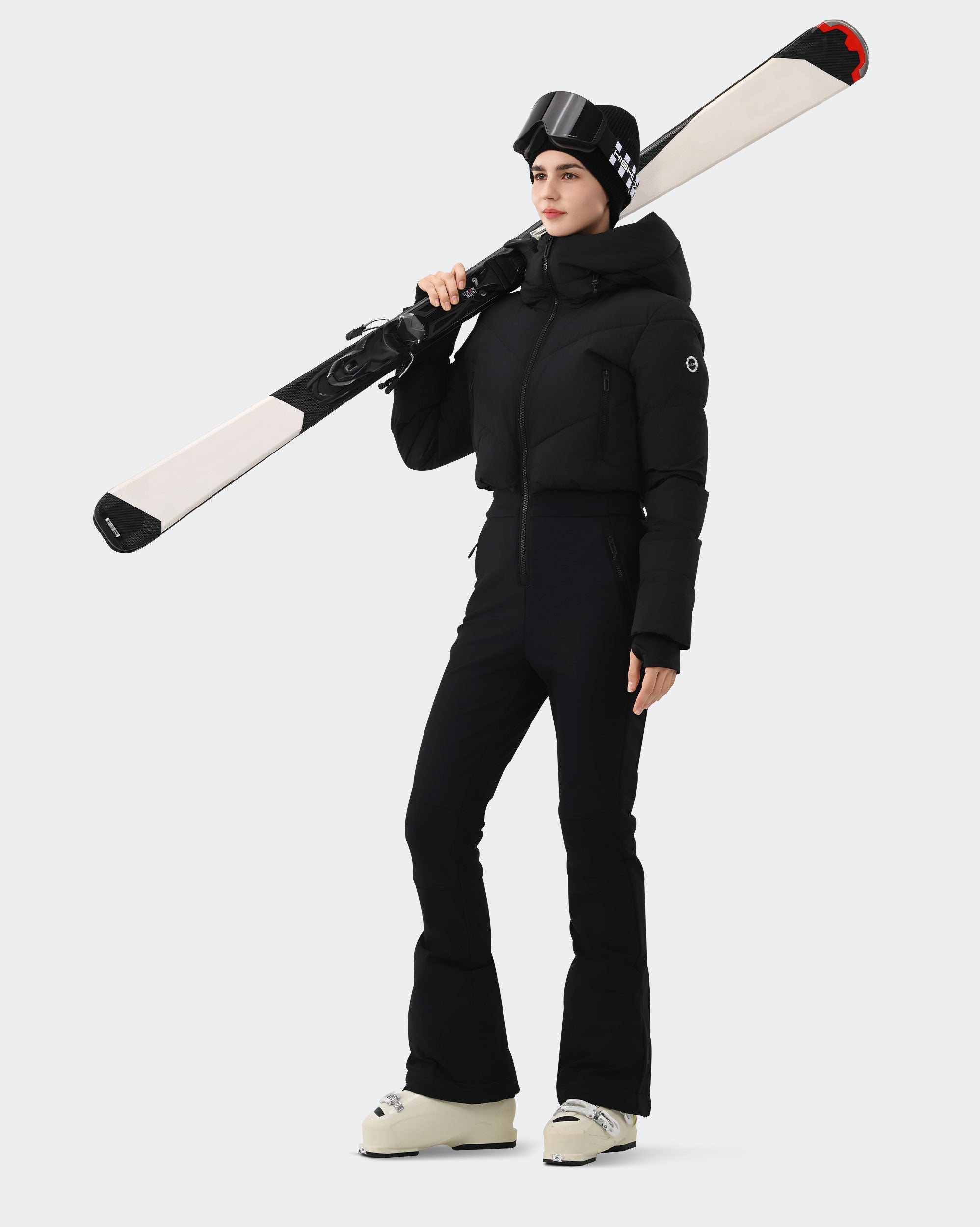 Woman wearing Black one-piece insulated ski suit on ski slope
